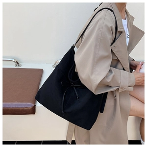Detail of black large capacity hobo tote bag featuring a decorative bow on the side