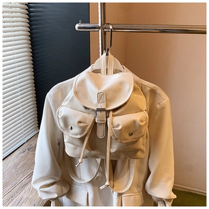 Detail of cream PU leather backpack with flap closure and dual pockets on a beige blazer