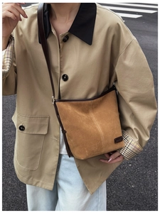 Gros plan d'un sac seau rétro en daim marron avec garniture en cuir porté par un mannequin