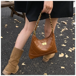 Détail d'un sac en cuir matelassé marron avec chaîne dorée et fermoir rotatif vintage