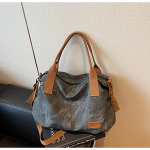 Detailed close-up of dark grey washed canvas tote bag with brown leather brand label