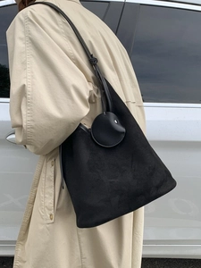 Minimalist black suede hobo bag styled on a beige trench coat for a casual autumn commute