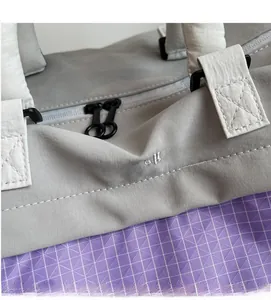 Macro detail of waterproof two-tone nylon fabric with reinforced stitching and zipper