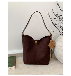 Detail of coffee suede tote bag with metal twist lock and cute plush bear charm