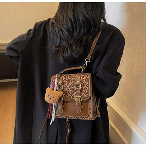 Detail showing high-quality leopard print texture with leather straps and bear charm