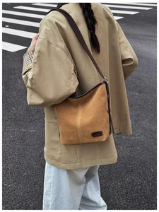 Vue de style urbain d'un sac cabas vintage en daim marron porté à l'épaule avec un manteau