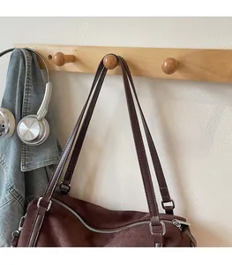 Detail of dark brown suede shoulder bag with zipper closure and durable metal hardware