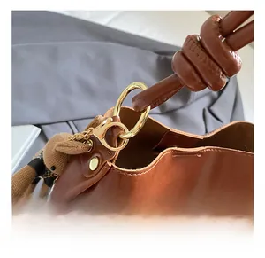 Detail of golden metal hook and decorative leather knot on a brown tote shoulder bag