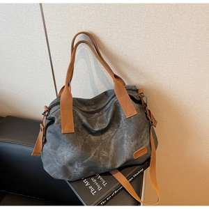 Detail of vintage grey washed canvas tote bag with brown leather tag and strap