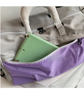 Detail showing the gray and purple travel bag with a large zipper pocket for a tablet