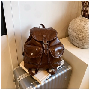 Detailed view of vintage brown PU leather backpack with contrast stitching on silver suitcase