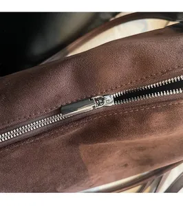 Detailed macro view of dark brown suede bag with premium silver metal zipper hardware