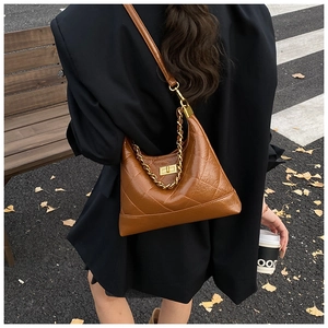 Sac hobo matelassé marron avec chaîne dorée porté par un mannequin dans la rue