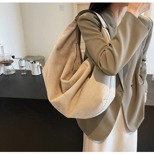 Gros plan d'un grand sac hobo en cuir mat beige montrant sa texture et son drapé
