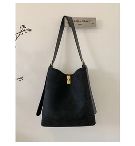 Detail of black suede tote bag with golden twist lock and minimalist shoulder strap