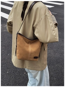 Gros plan sur le sac seau en daim marron rétro avec bordures en cuir et logo discret