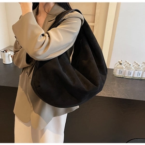 Détail d'un sac cabas noir en daim mat porté avec un style urbain moderne par un mannequin