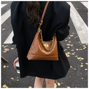 Détail d'un sac marron matelassé avec finition brillante et chaîne dorée