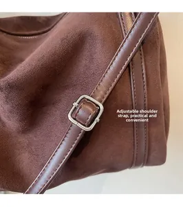 Detail of adjustable shoulder strap with silver buckle on brown suede tote handbag