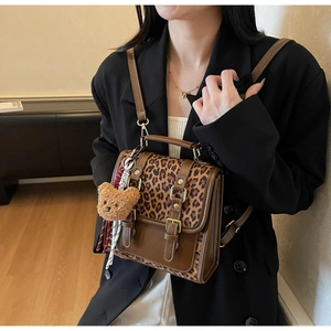 Detail view of leopard print backpack with leather straps and cute plush bear charm