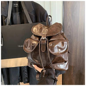Detail of dark brown vintage faux leather backpack with metallic buckle and drawstring closure