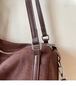 Detailed close-up of dark brown suede bag featuring silver D-ring and smooth leather strap