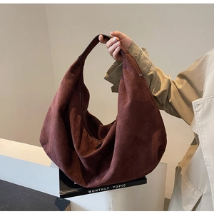 Gros plan sur la texture en cuir suédé bordeaux et les coutures du grand sac hobo