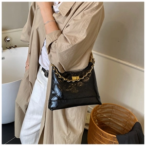Détail d'un sac bandoulière matelassé noir avec chaîne dorée et fermoir en métal