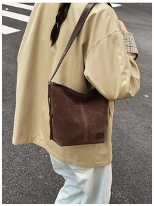 Gros plan d'un sac seau en daim marron avec étiquette de marque en cuir et bandoulière