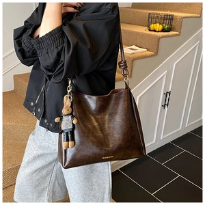 Close-up of dark brown vintage PU leather hobo bag with a cute rabbit doll pendant