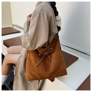 Detail of vintage brown suede tote bag featuring chic bow drawstring decoration