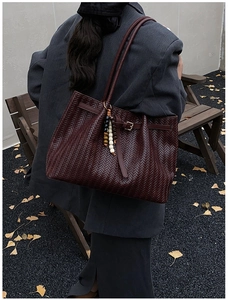 Outdoor shot of dark burgundy woven leather tote bag with colorful beaded charm