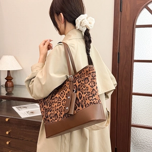 Detail of leopard print tote bag with brown leather base shown on model's shoulder