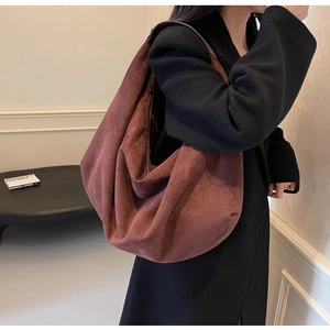 Vue de côté du grand sac hobo en daim marron foncé montrant son drapé naturel et sa texture