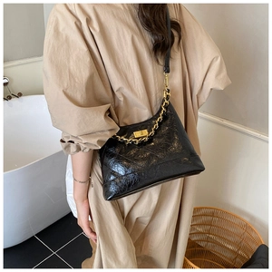 Gros plan d'un sac noir matelassé avec chaîne dorée et fermoir métallique carré chic