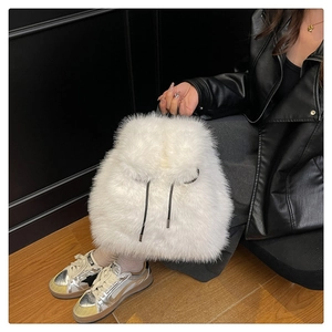 Detail of white faux fur backpack featuring a soft plush texture and drawstring closure