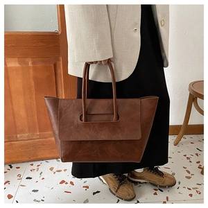 Close-up of deep brown vintage tote bag showing textured PU leather and handle structure