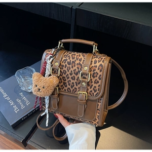 Detail of leopard print backpack with retro buckles and a cute plush bear charm