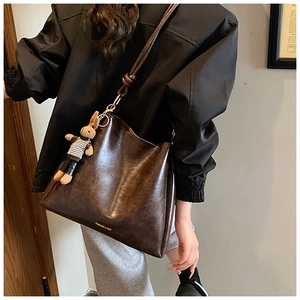 Detailed side view of vintage brown tote bag with a cute rabbit doll charm and gold logo
