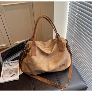 Close-up of a large vintage brown tote bag with canvas straps near a laptop on a desk