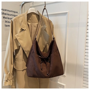 Close-up of a vintage brown suede tote bag with drawstring bow detail on a hanger