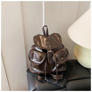 Detail of vintage dark brown travel backpack showing wax leather texture and buckled pockets
