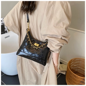 Gros plan sur le sac en cuir verni matelassé noir avec chaîne dorée et fermoir pivotant