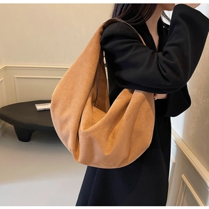 Détail d'un grand sac cabas en daim mat marron porté avec élégance par un mannequin