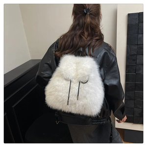 Back view of a fluffy white faux fur backpack with drawstrings on a female model