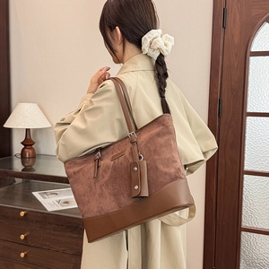 Detail showing the brown suede texture and side mini bag accessory of the tote bag