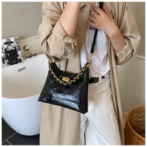 Détails de la texture en cuir noir matelassé et de la bandoulière chaîne dorée du sac