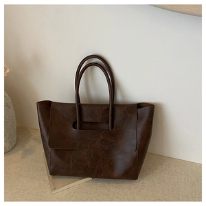 Detail of dark brown faux leather tote bag showing unique cutout flap and textured surface