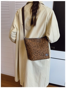Détail du sac seau imprimé léopard avec bandoulière en cuir brun et logo en métal