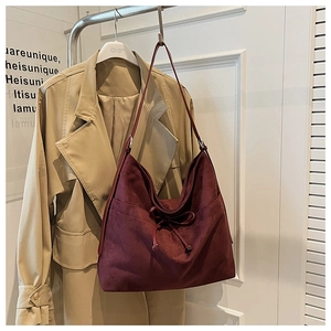 Detail of burgundy suede tote bag featuring a decorative bow tie and retro design